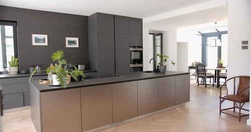 A modern kitchen features sleek dark cabinetry and a central island