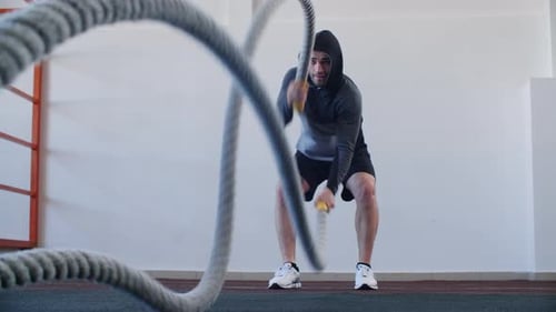 Young Sportsman Working Out with Battle Rope in Gym