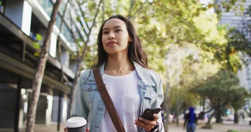 Woman Using Phone and Walking in the City