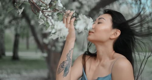Young Woman Smelling Apple Blossoms in an Orchard
