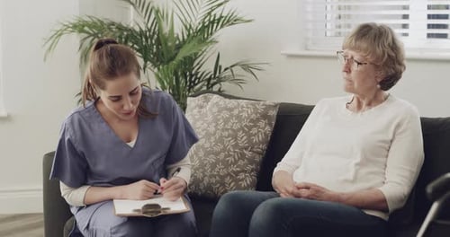 4k video footage of a female nurse sitting down for a consultation with one of her elderly patients