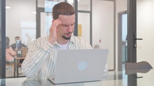 Young Adult Massaging Temples at Desk