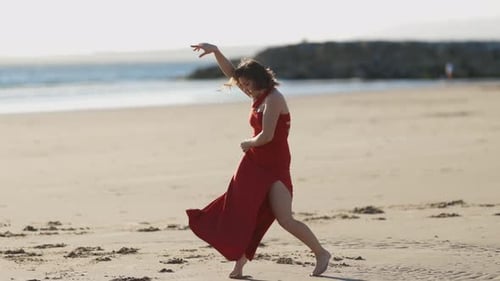 Woman in Red Dress Dancing on the Beach