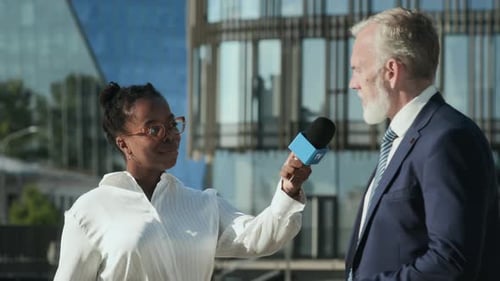 Woman Interviews Man in Front of Modern Office Building