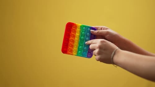 Woman's Hands Manipulate Rainbow Pop-It Fidget Toy