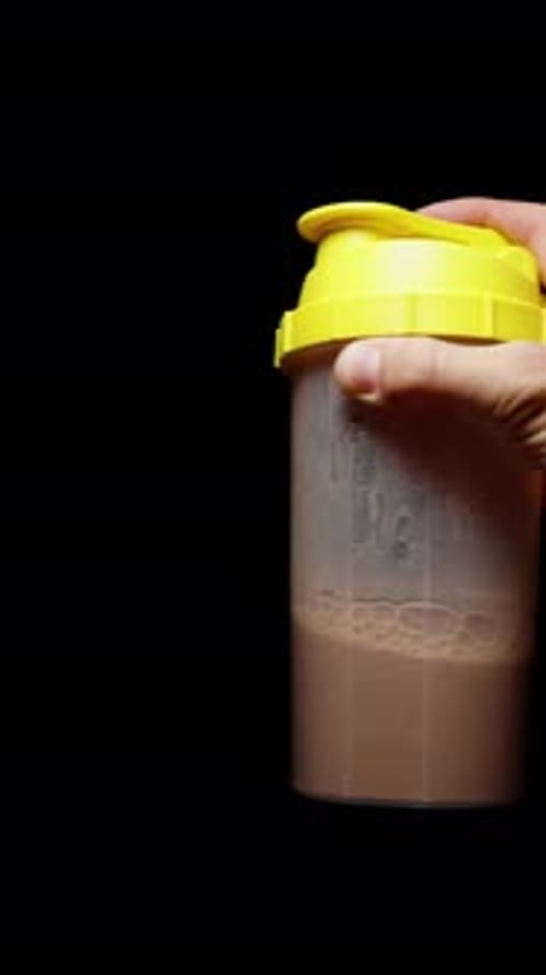 Vertical video. Shaking a Sports Drink in a Shaker, Preparing a Protein Shake. Slow-Motion.