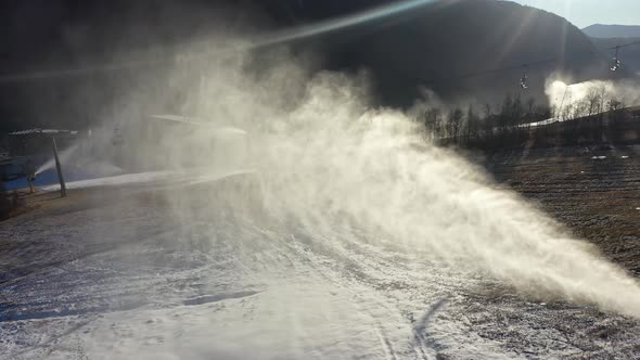 Snow spray from artificial snow production with beautiful sunset light ...