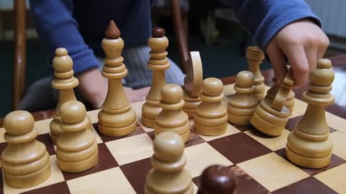 A Little Boy is Playing Chess Moves the Knight Piece on the Chessboard