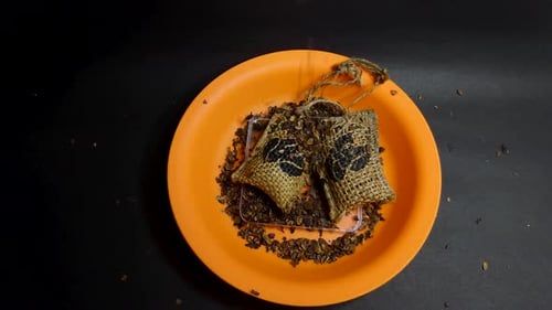 Small Burlap Sacks with Brown Particles on Orange Plate