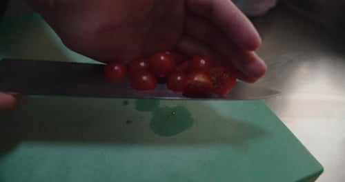 Amazing slow motion tracking shot of a chef's hands carrying small chopped Cherry tomatoes into a st