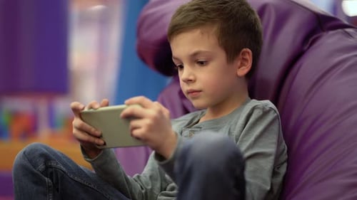 Boy Playing Mobile Game on Cell Phone Indoors