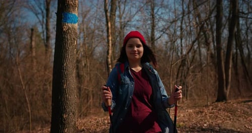 Backpacker Hiker Girl with Hiking Poles Walking Between Trees in a Mountain Forest Hispanic Teenager
