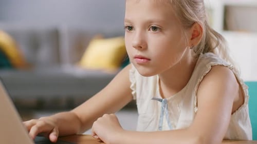 Concentrated Girl Using Laptop at Table Inside Home