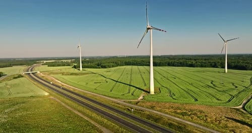 Wind turbines and green field near highway, aerial view