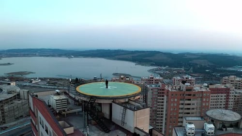 Hombre de pie en el helipuerto de la azotea con vistas a la ciudad y el lago
