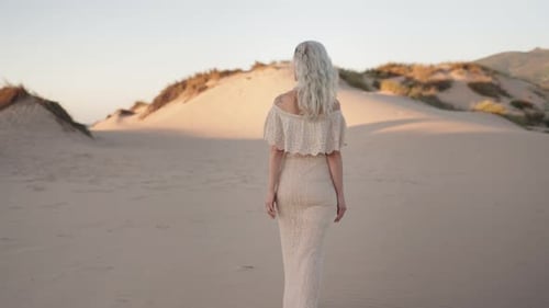 Mature Woman in White Dress Walks Through Desert Landscape at Golden Hour Embracing Freedom Solitude