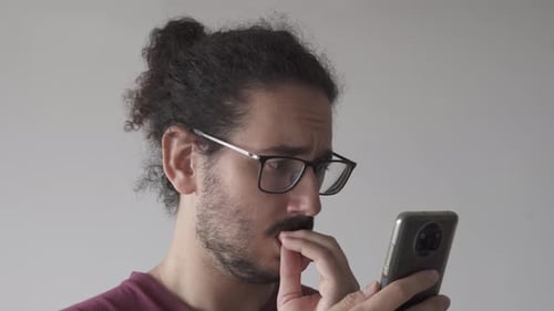 Close up of anxious man looking at smartphone and biting his nails