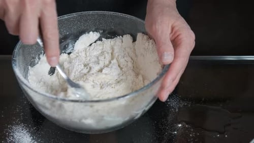 Hands Mixing Dough in Bowl with Spoon