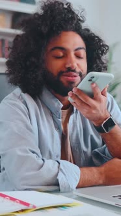 Young Man Engages in an Insightful Conversation on His Smartphone in a Cozy Cafe
