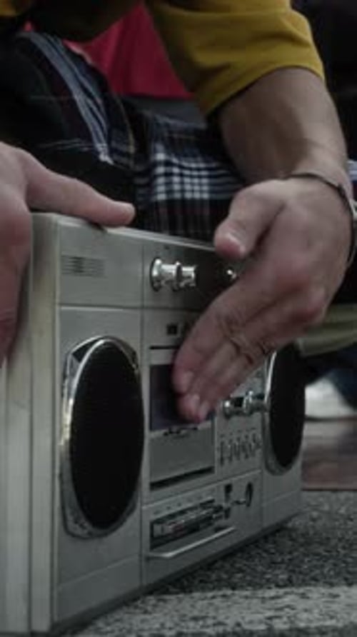 Vertical of Unrecognizable Guy Loading Cassette into Silver Retro Boombox