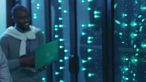 In a Data Center a Woman Analyzes Data While a Man Works on Laptops