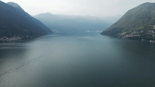 A tilting drone shot showcasing a wide, mountainous vista from above Lake Como in Italy.