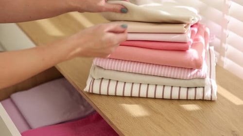 Woman putting clothes into drawer of cabinet indoors, closeup