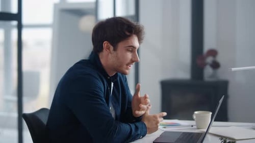 Smiling businessman explaining project on laptop video call at modern office