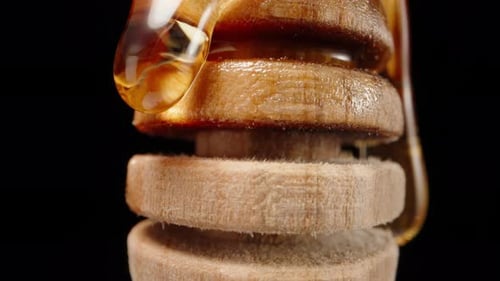 Wooden spoon for honey, spin and honey flows down, macro shot