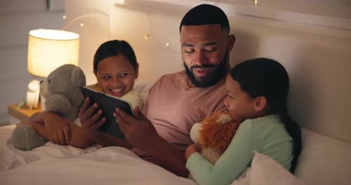 Dad and Daughters Using Tablet in Bed at Night