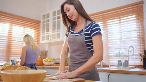 Caucasian young woman baking bakery with friend in kitchen at home.