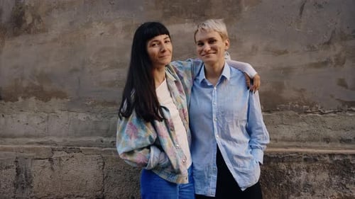 Two Women Smiling in Front of an Old Wall