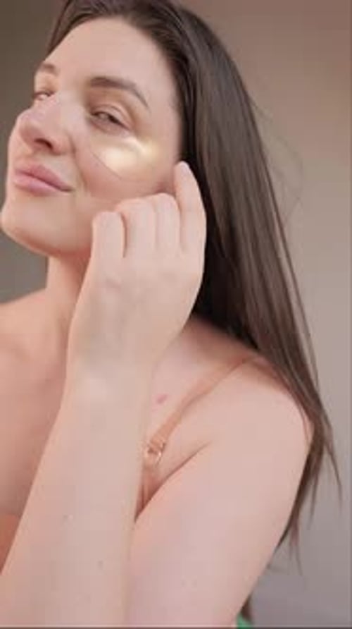 Woman Applying Gold Cosmetic Eye Patches