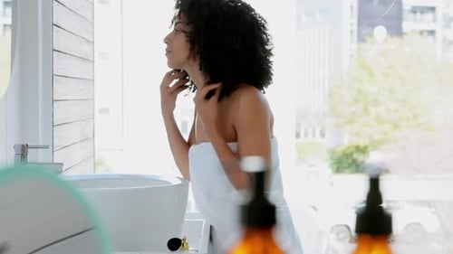 Woman Styling Hair in Bright Bathroom Mirror