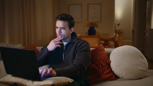 Man Using Laptop on Couch at Night