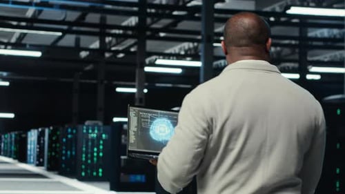 Técnico usando laptop no data center gerenciando a virtualização de servidores