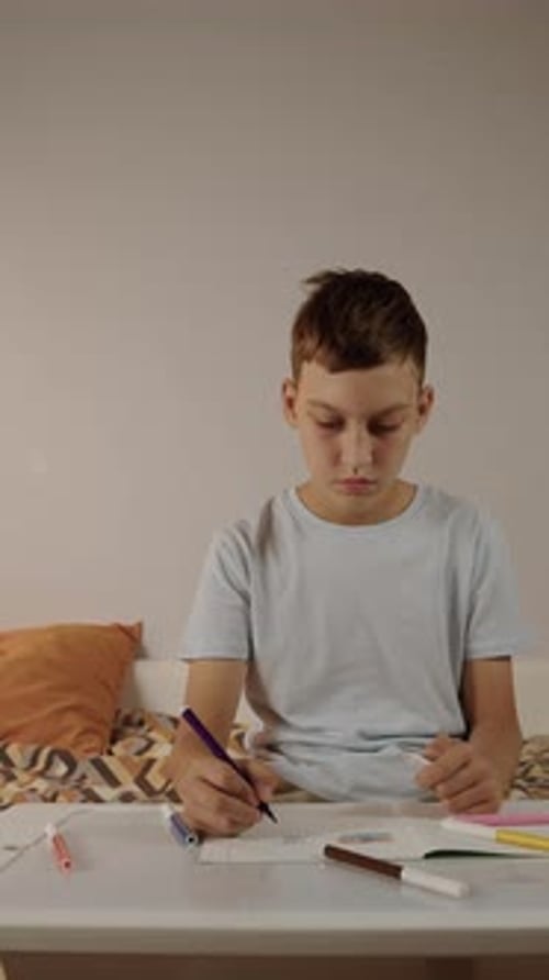 Boy Writing in Notebook at Study Desk