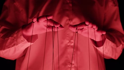 The Puppeteer Controls the Puppets in the Theater in Red Neon Light Closeup Managing People at Work