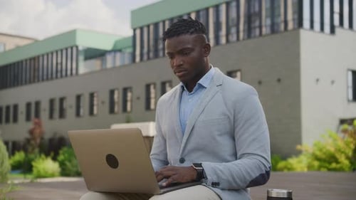 Young Adult Working on Laptop Outdoors in City
