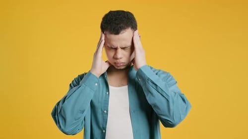 Young Man Having Headache Studio Portrait Guy Putting Hands on Head Isolated on Yellow Background
