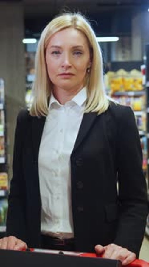 Woman Standing in Supermarket with Shopping Cart