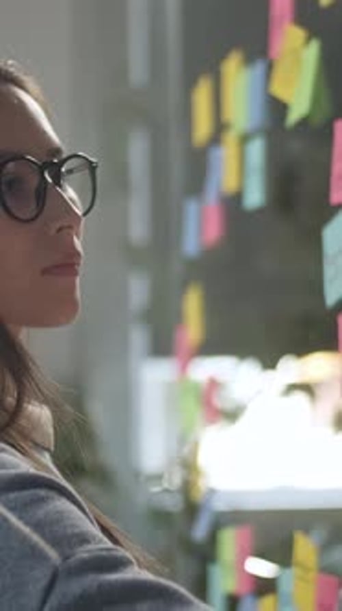 Woman writes on sticky notes on glass wall