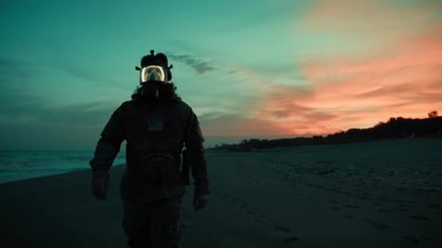 Silhouette of a Soldier with Gas Mask Walks on the Beach at Sunset