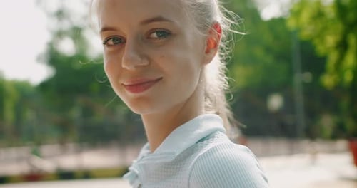 Portrait of young attractive woman walking in park and looking at camera