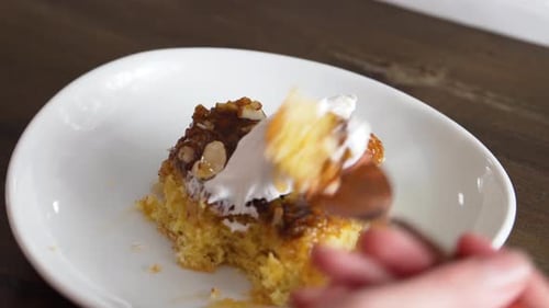 Persona comiendo un trozo de pastel de plátano con caramelo dulce cubierto con nueces y glaseado. - Toma de ángulo alto