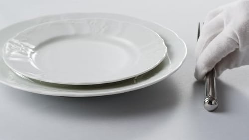 Setting Table with Shiny Silver Cutlery and Plates