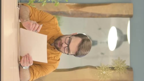 Man Reading and Writing on Paper at Desk