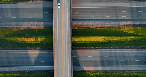 Vehicles ride by the highways and freeways above them. Not busy traffic by the roads at sunset.