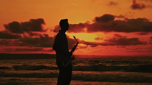 A Saxophonists Silhouette Beautifully Portrayed Against a Stunning Sunset Backdrop at the Beach