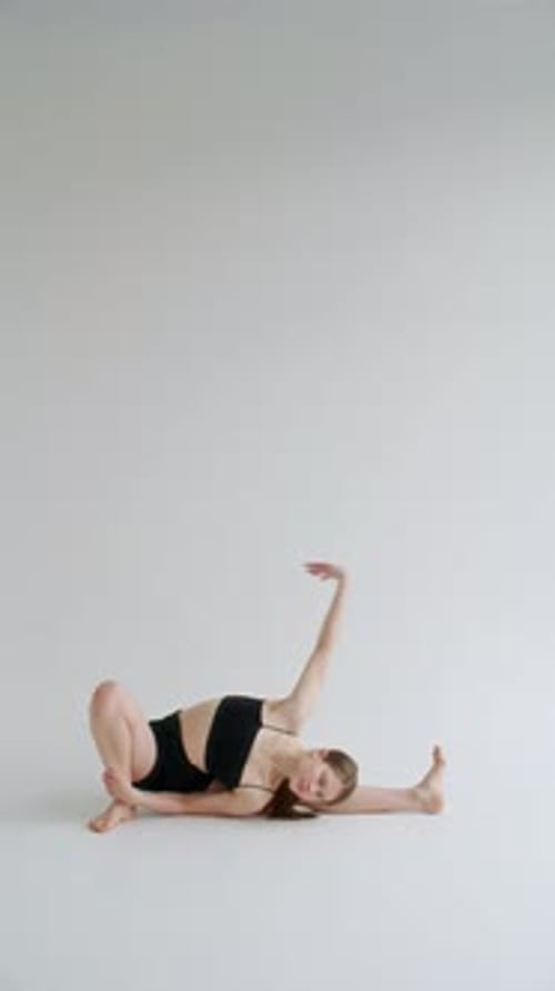 Chica estirándose en posturas de yoga avanzadas en estudio con fondo blanco